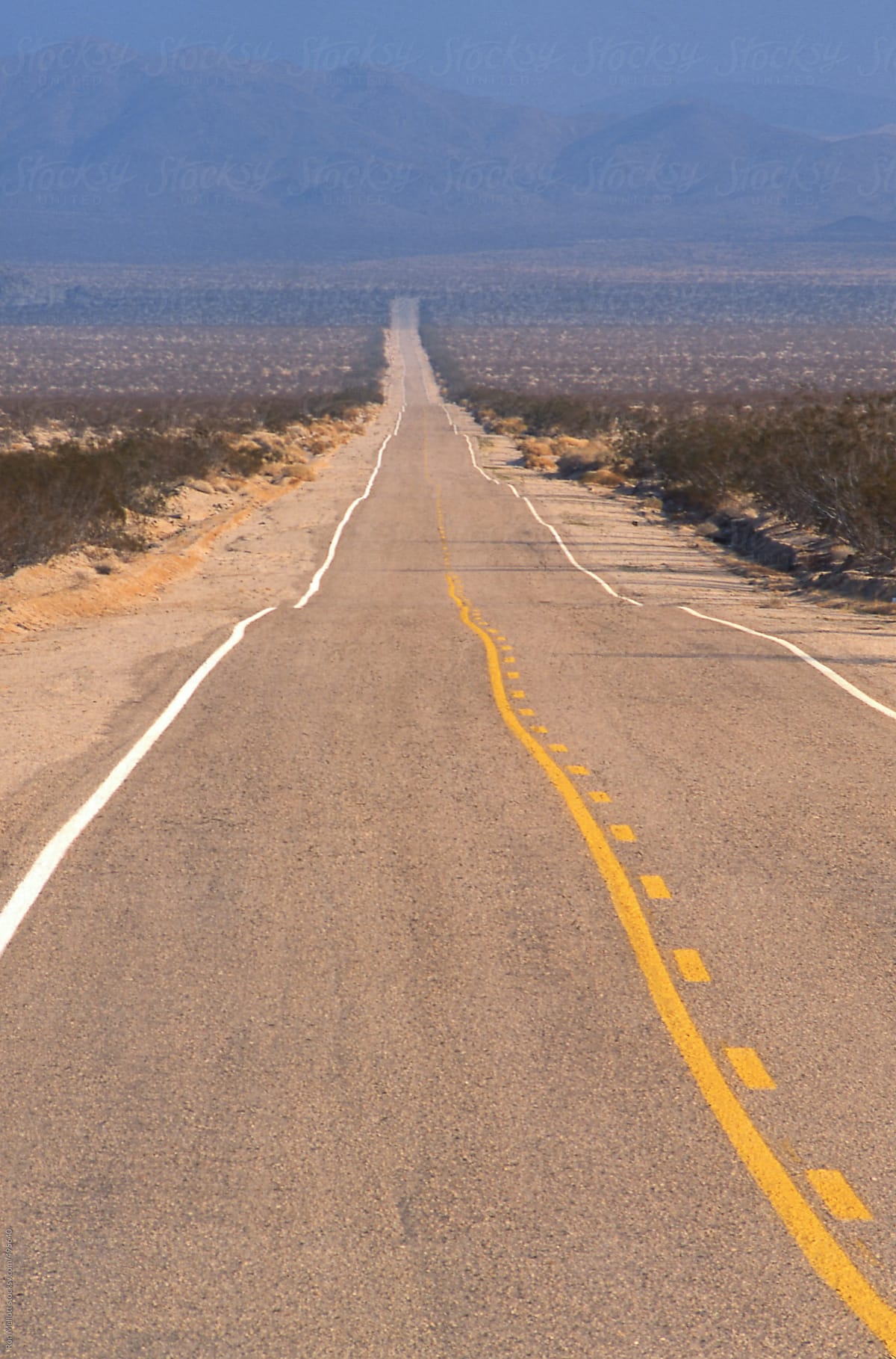 paved asphalt road Mojave desert California two-lane straight shrubs