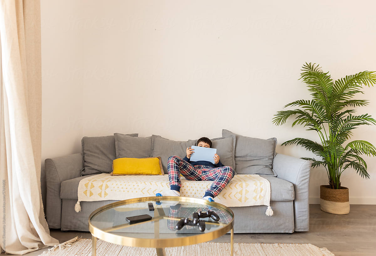 a boy in sleepwear lying on the sofa at home