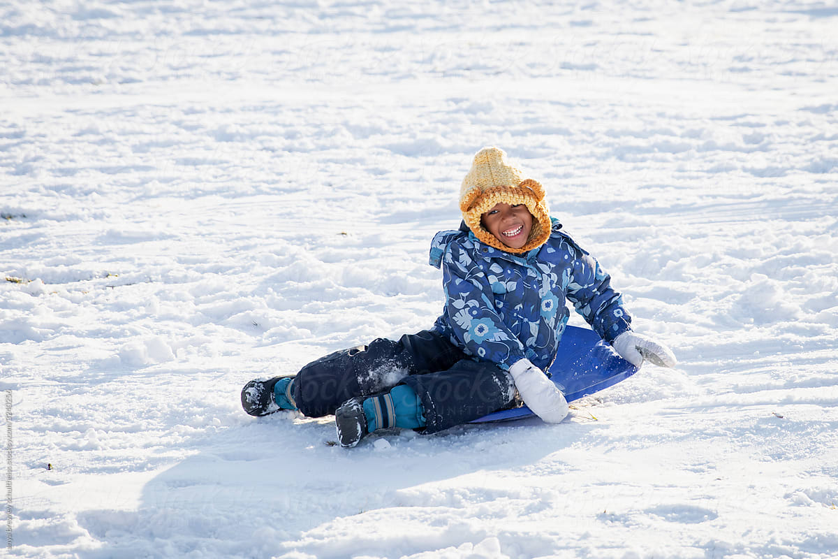 Happy boy sitting on a blue sled