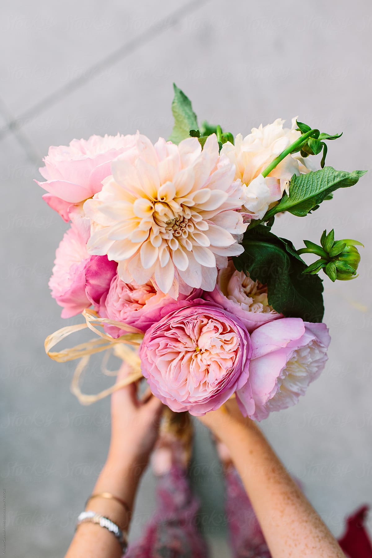 A first person view of someone holding a dahlia & garden rose arrangement.