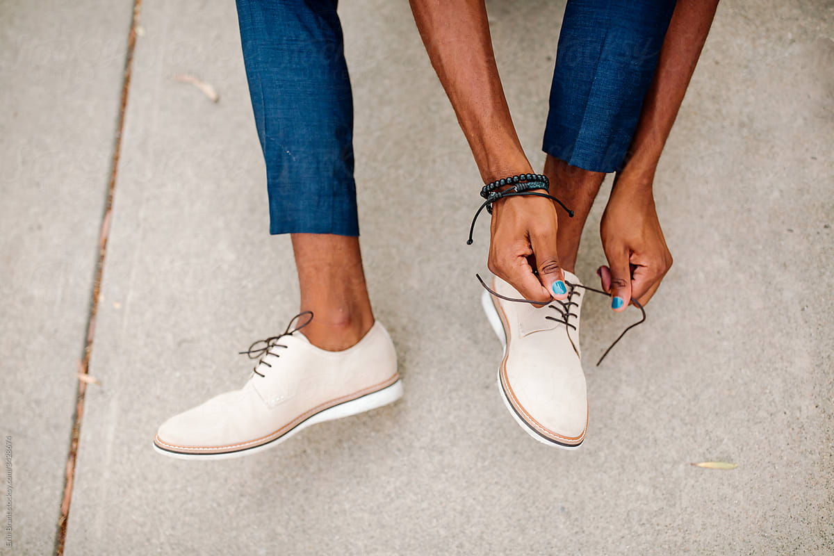 Lower legs of black male tying shoes