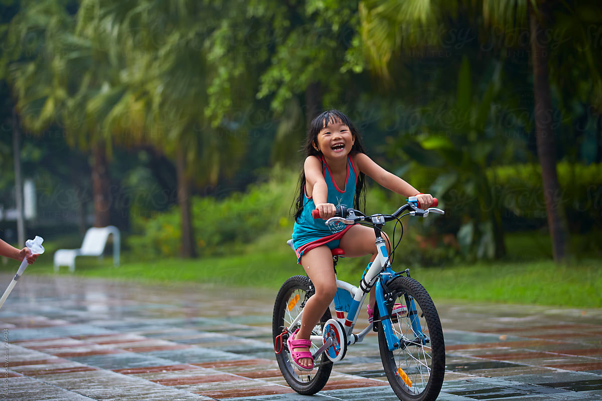 Little Asian Girl Riding Bike In The Park By Stocksy Contributor Bo