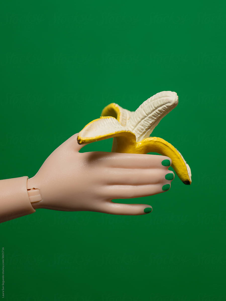 Plastic hand with green nails holding an open banana