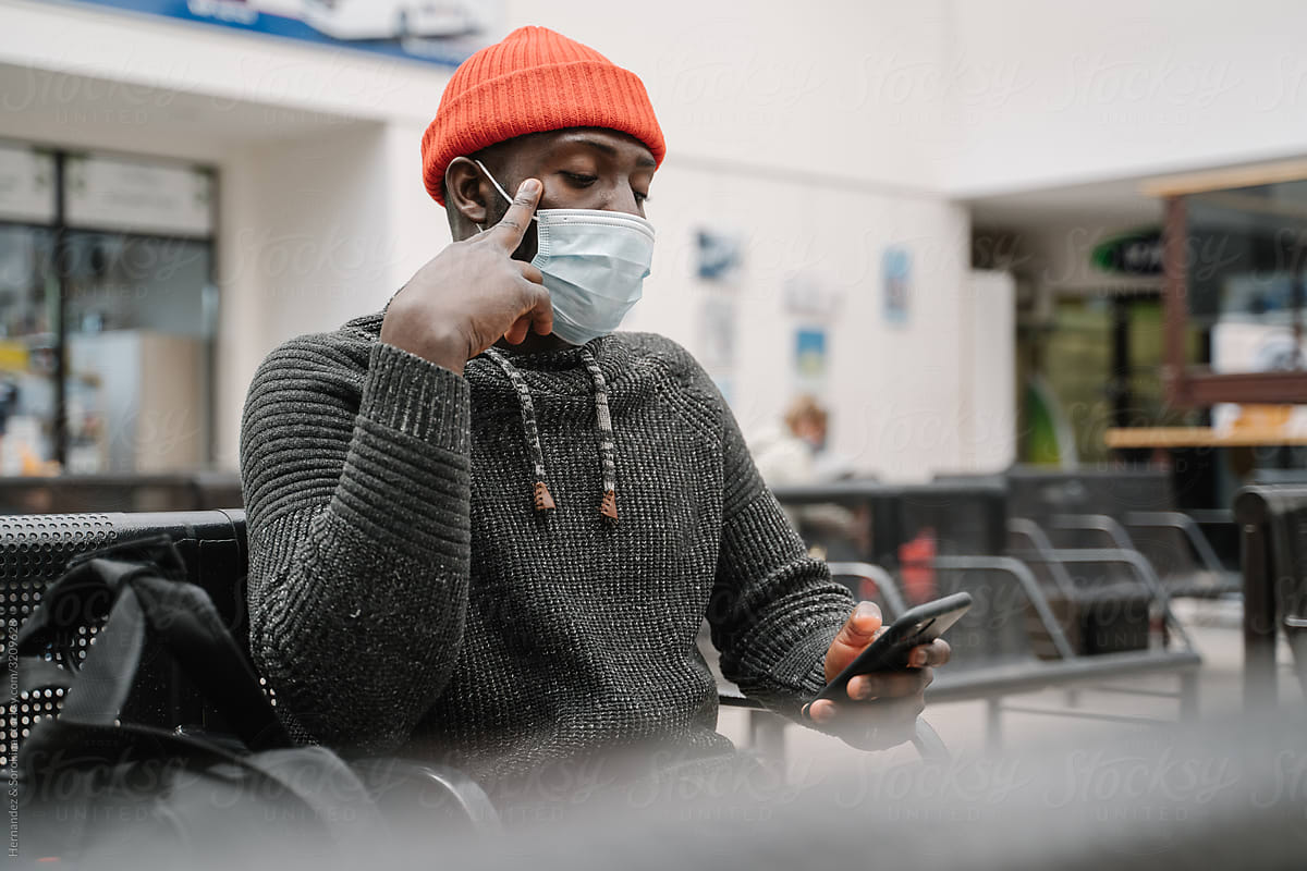 Black Man Wearing Face Mask Using Cellphone In The Station