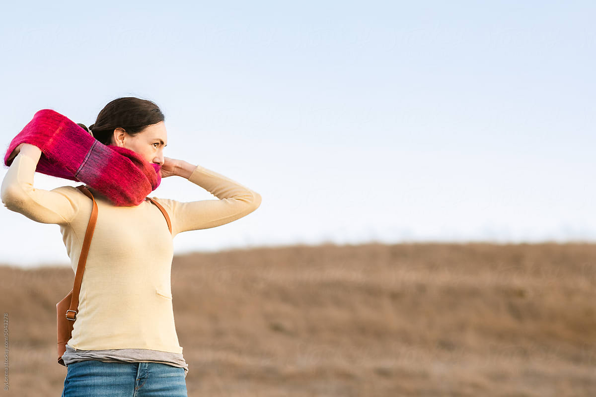 Woman taking off scarf walking through the field