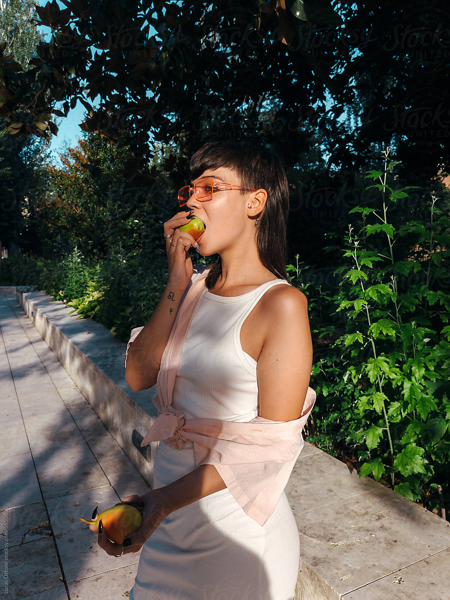 Young hungry woman biting a fruit