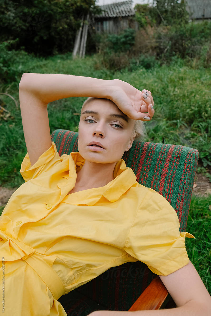 beautiful and stylish girl in a yellow retro dress, who sits in a chair