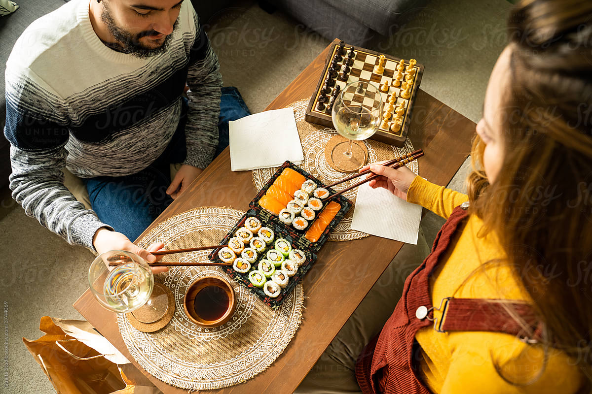 Couple having sushi on coffe table in living room