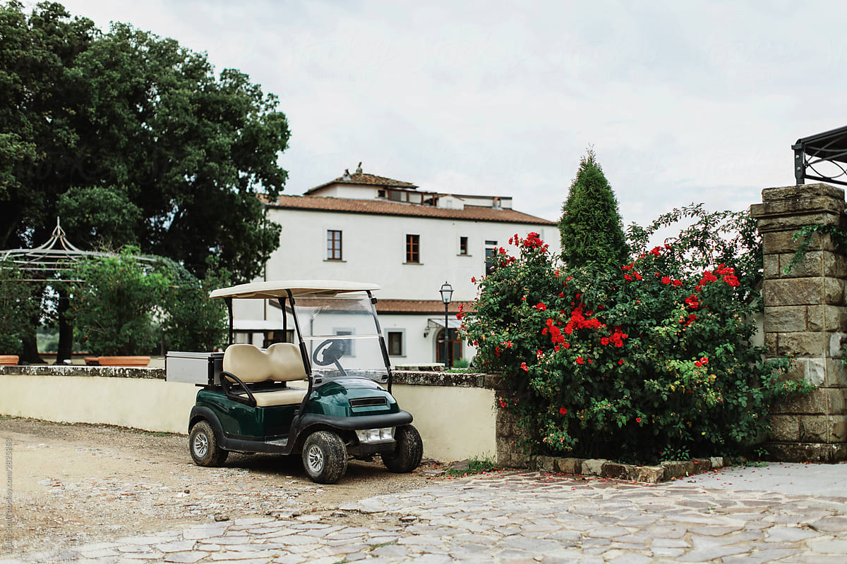 Golf cart parked close to red roses plant in front of country villa