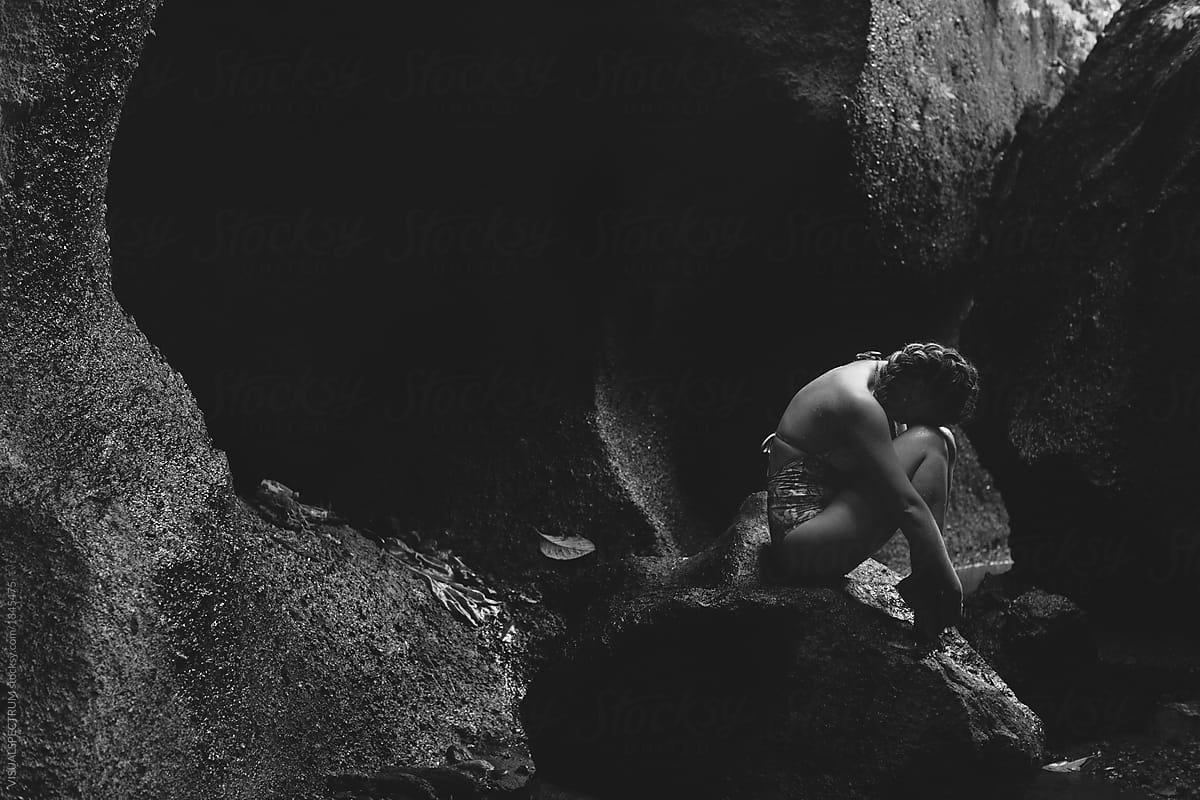 Black and White Shot of Young Woman in Swimsuit Sitting in Rock