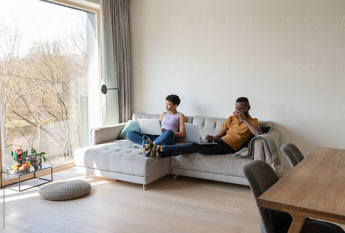 Couple Using Laptops On Couch