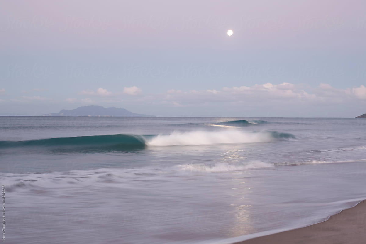 Breaking waves and full moon at dusk