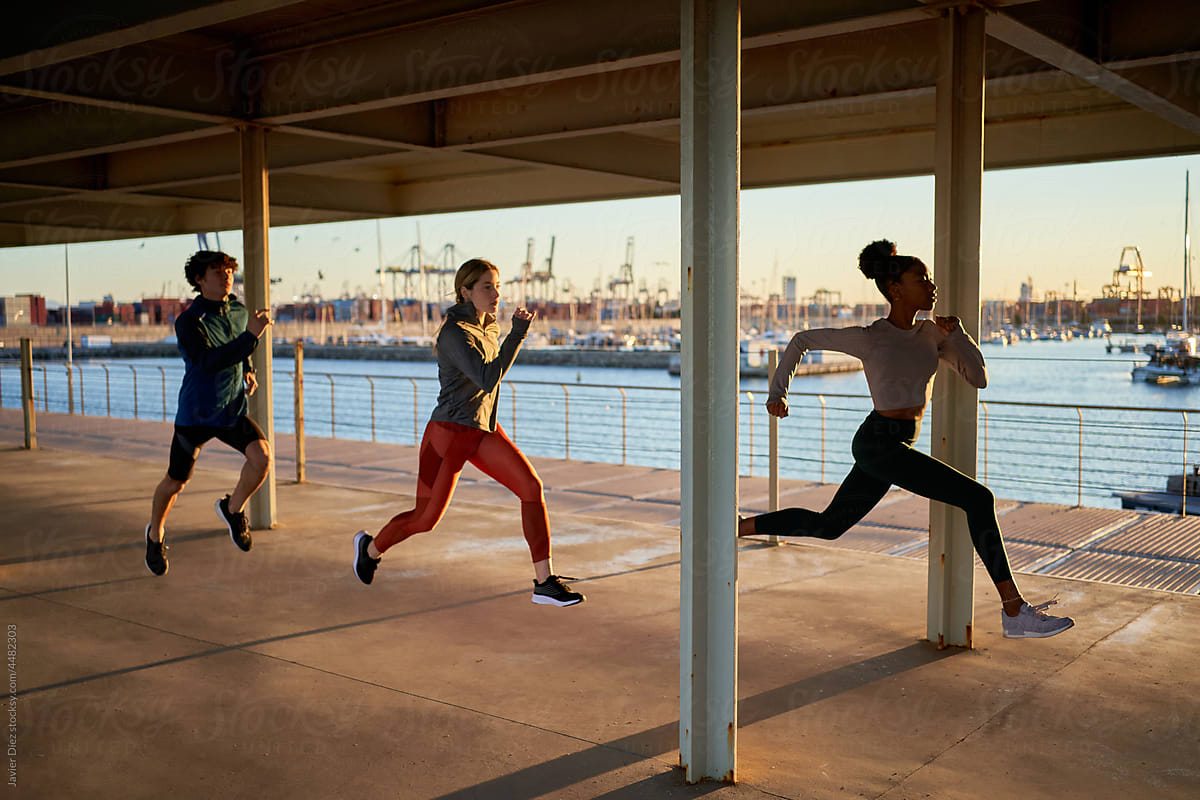 Diverse Athletes Jogging At Pier by Stocksy Contributor Javier