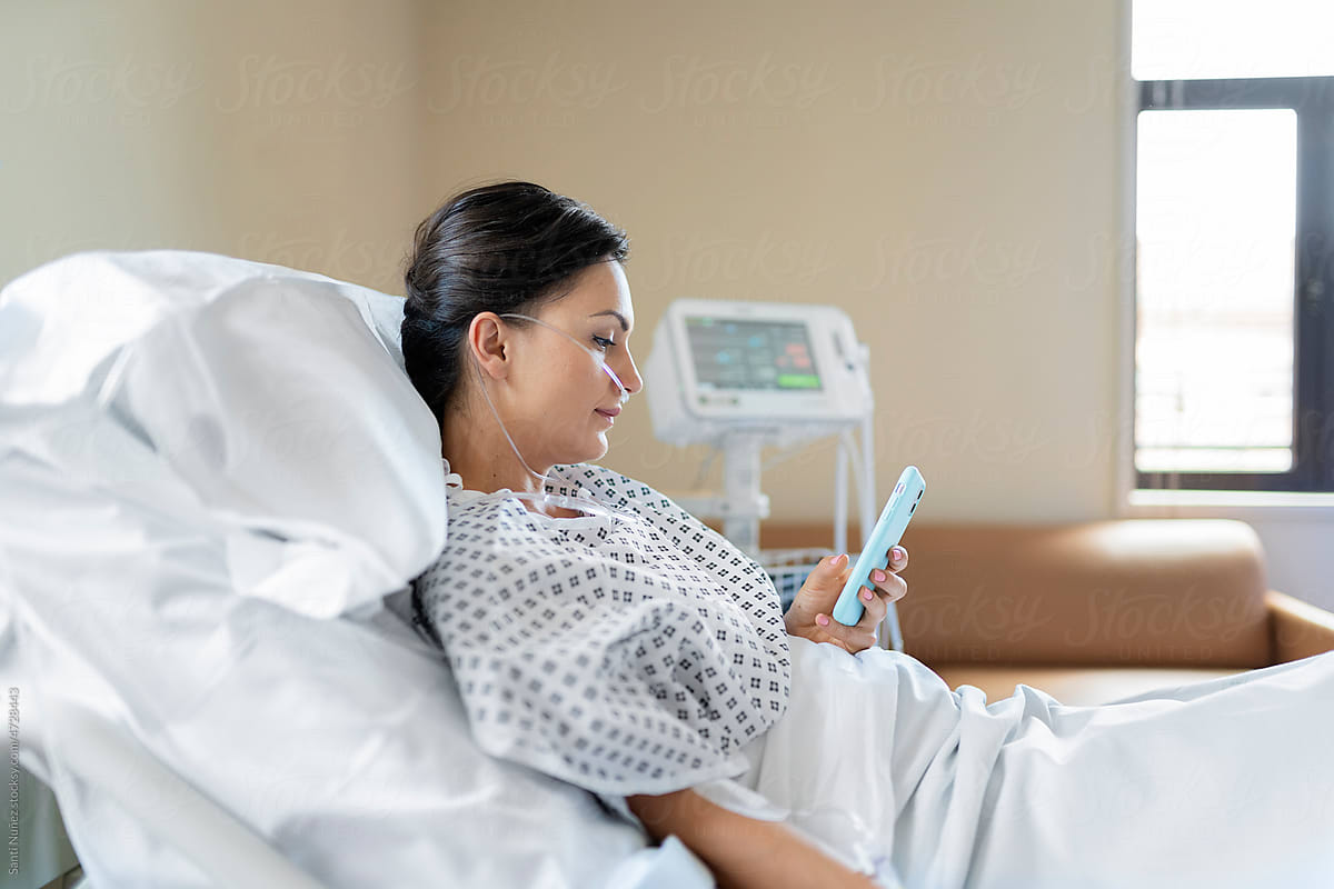 Patient woman using mobile in a hospital bed