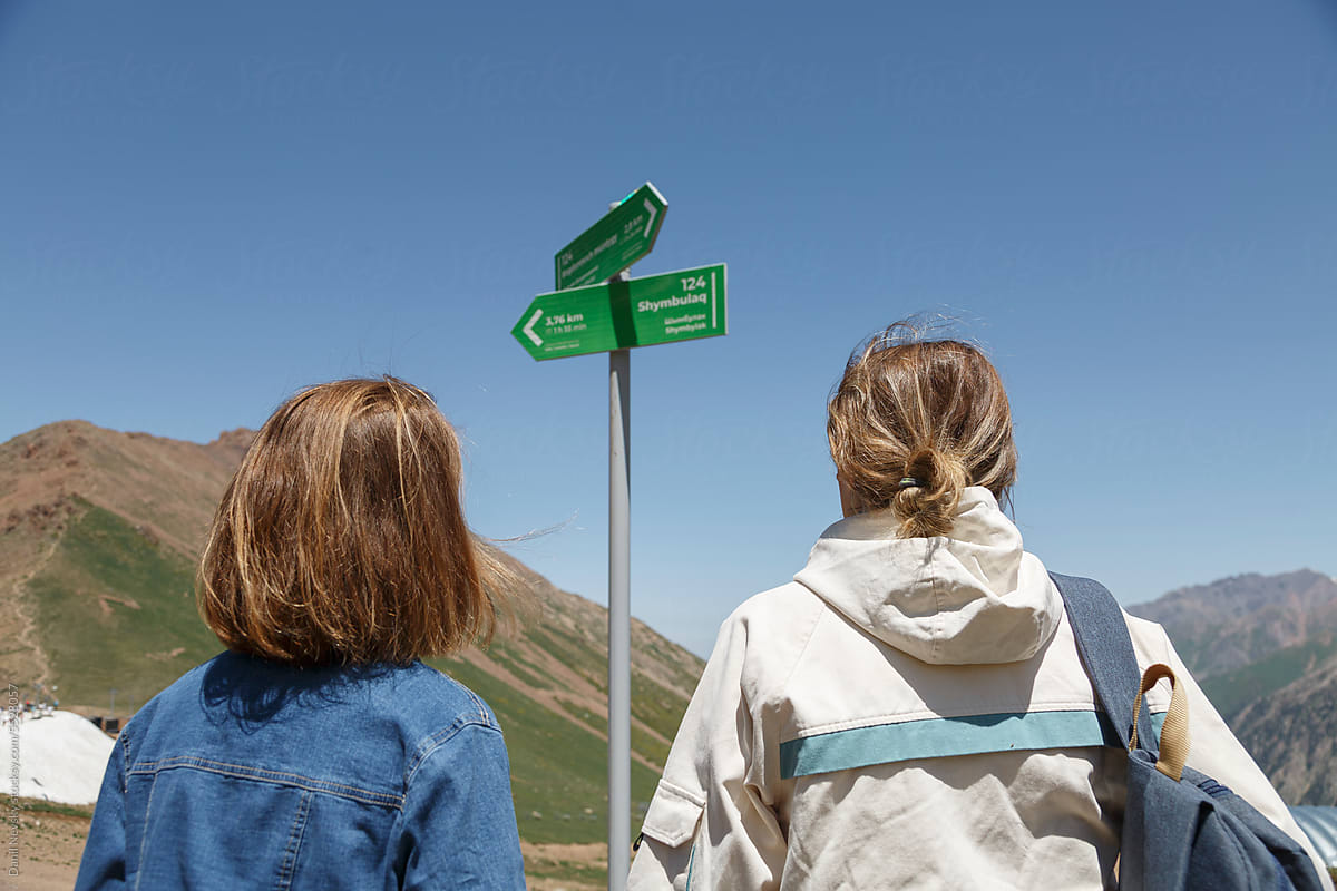 Traveling women near pointer sign in mountains