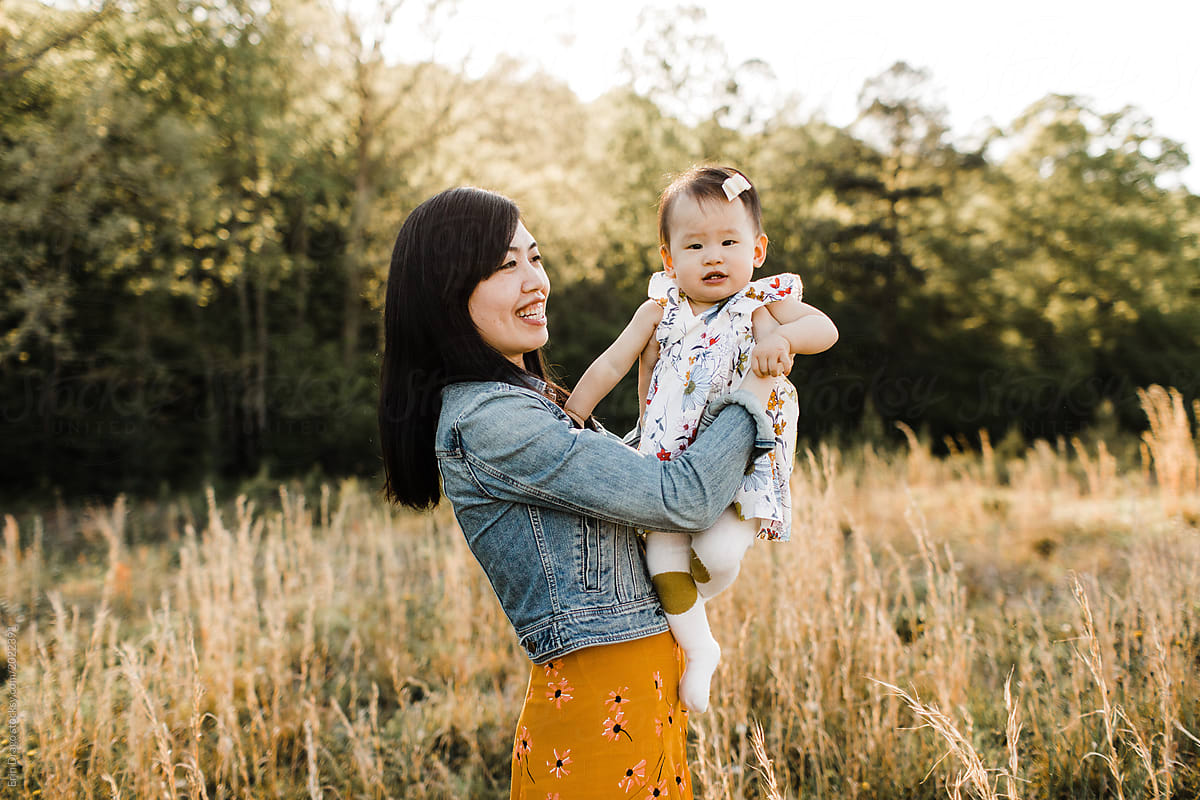 Asian Mom And Daughter Snuggling Cuddling And Playing Outdoors By Stocksy Contributor Erin