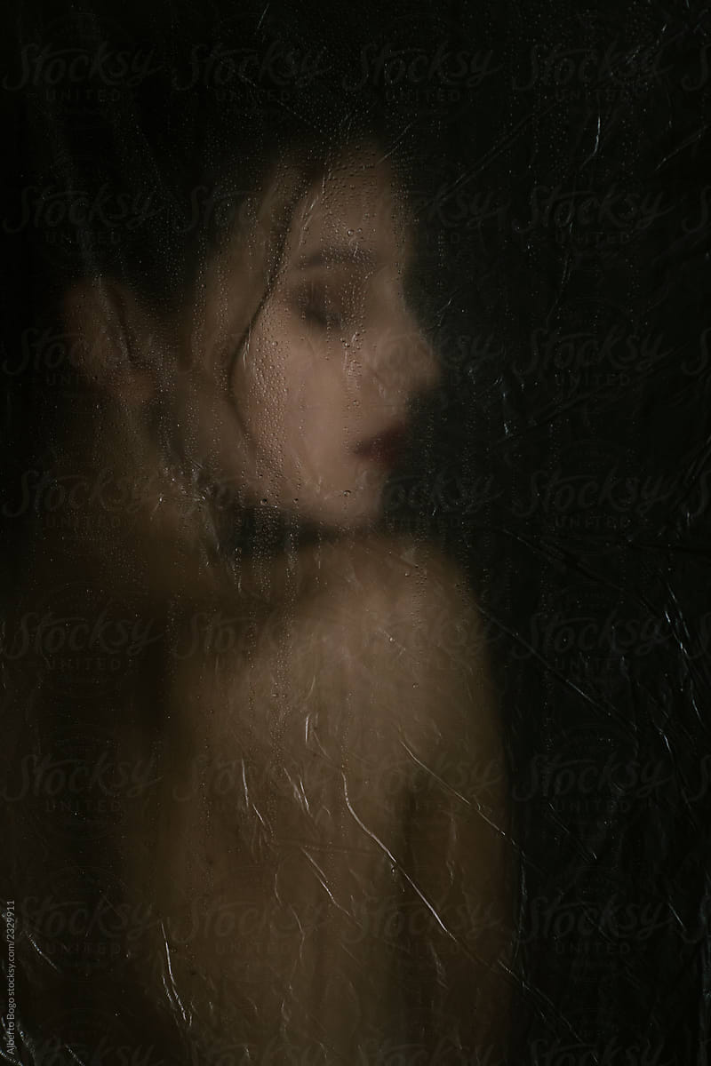 Sensual woman in dark behind plastic