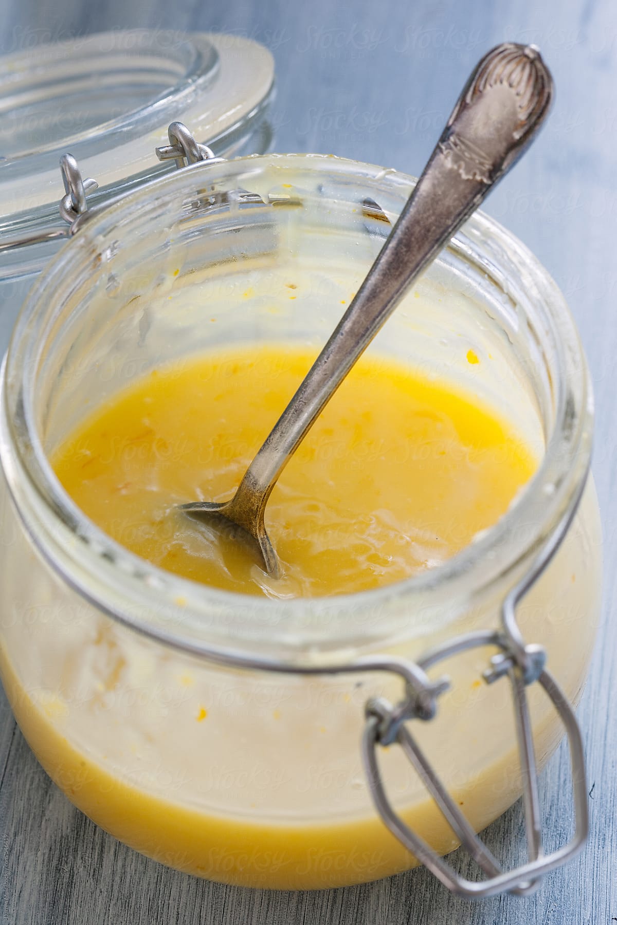Open jar of homemade orange curd with spoon.