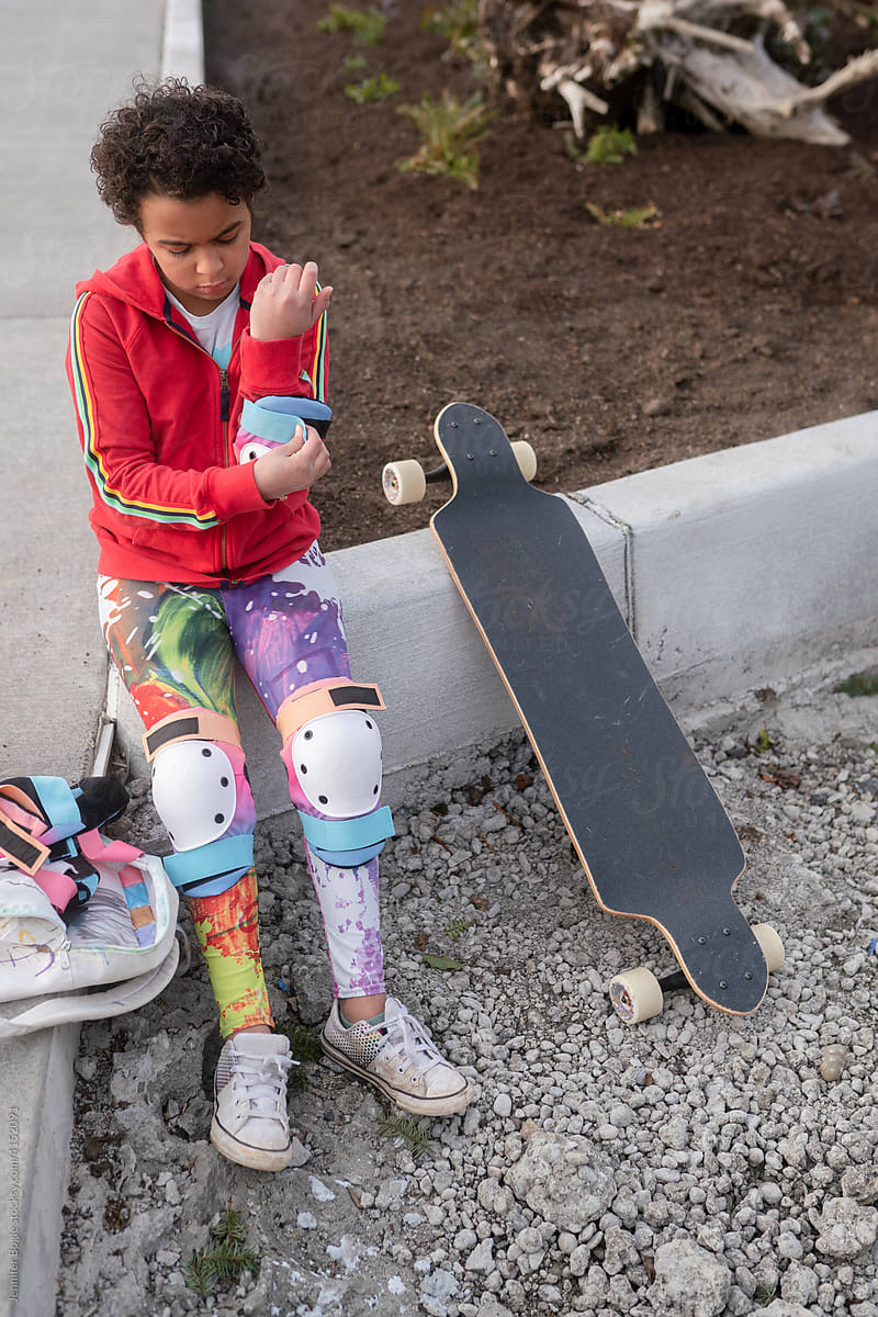 Girl with skateboard fastens elbow pads