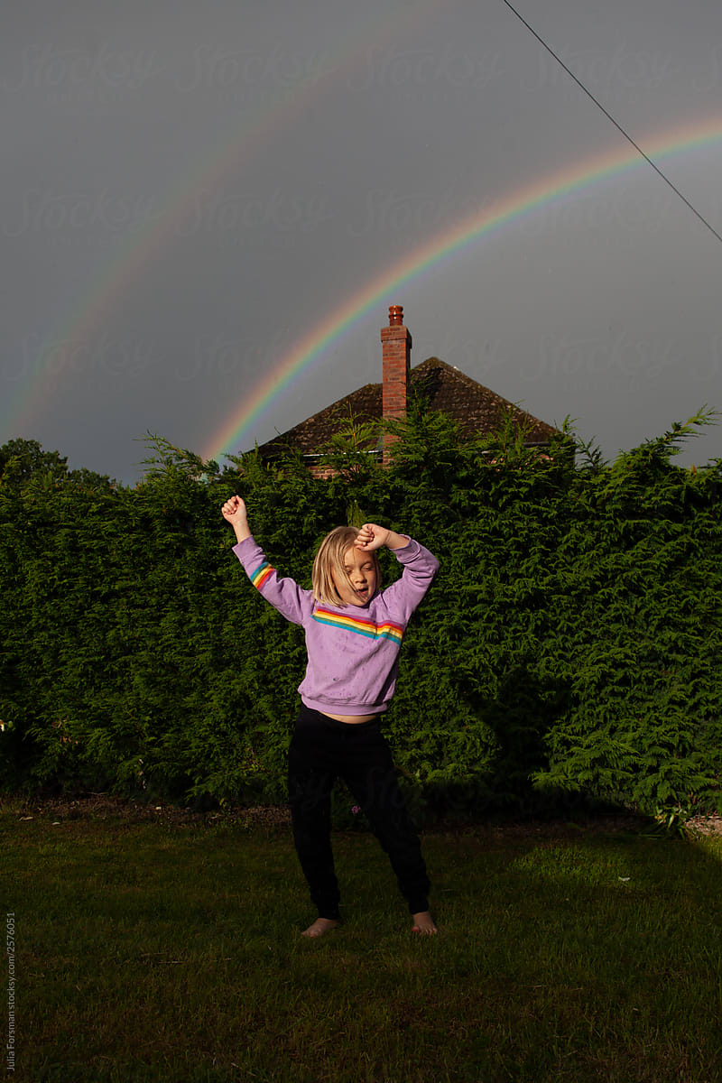 Rainbow magic. A girl dances in the rain.