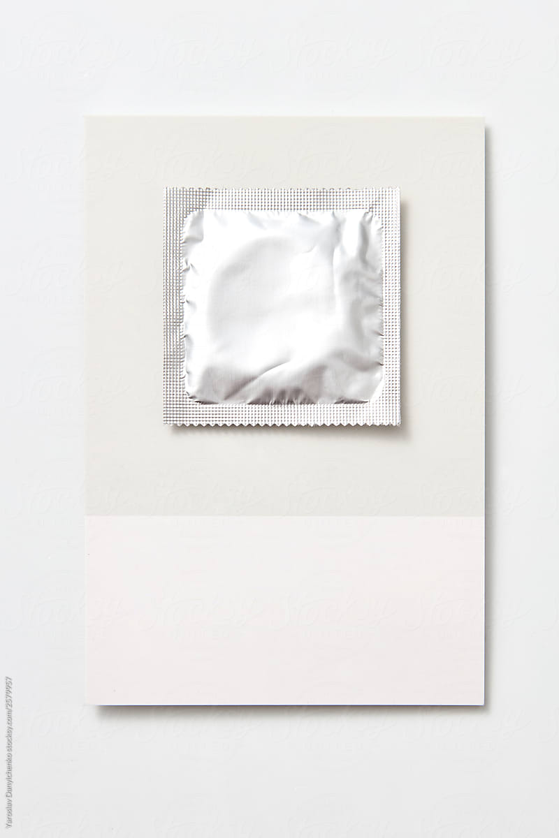 Silver colored condom on a grey card.