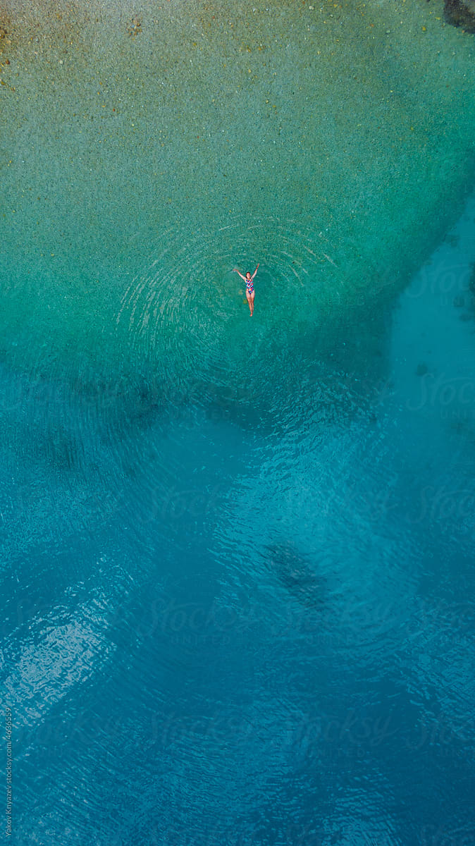 beautiful woman relaxing in a blue sea water, drone overhead