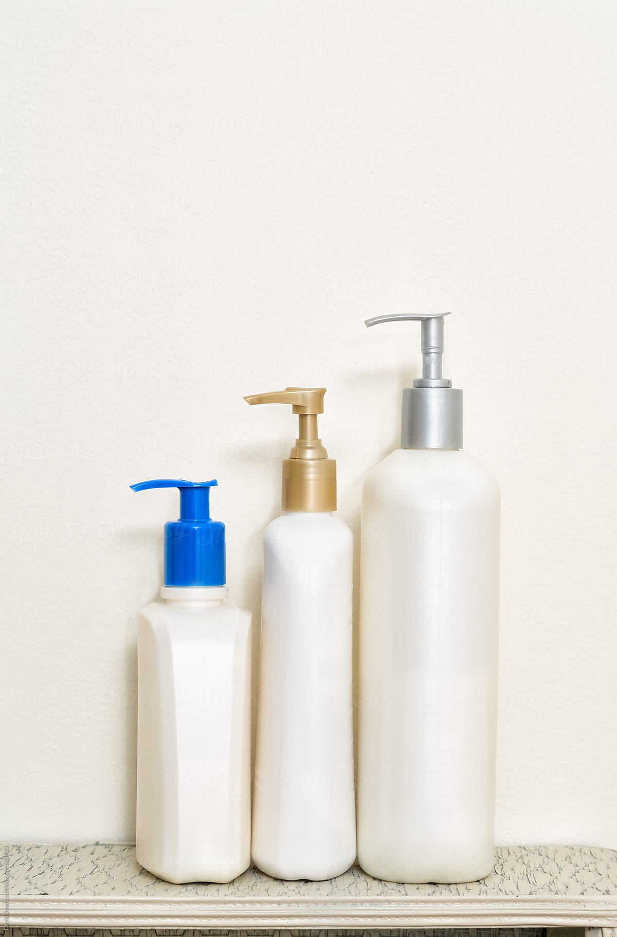 Three hand and body lotion bottles with pump dispensers