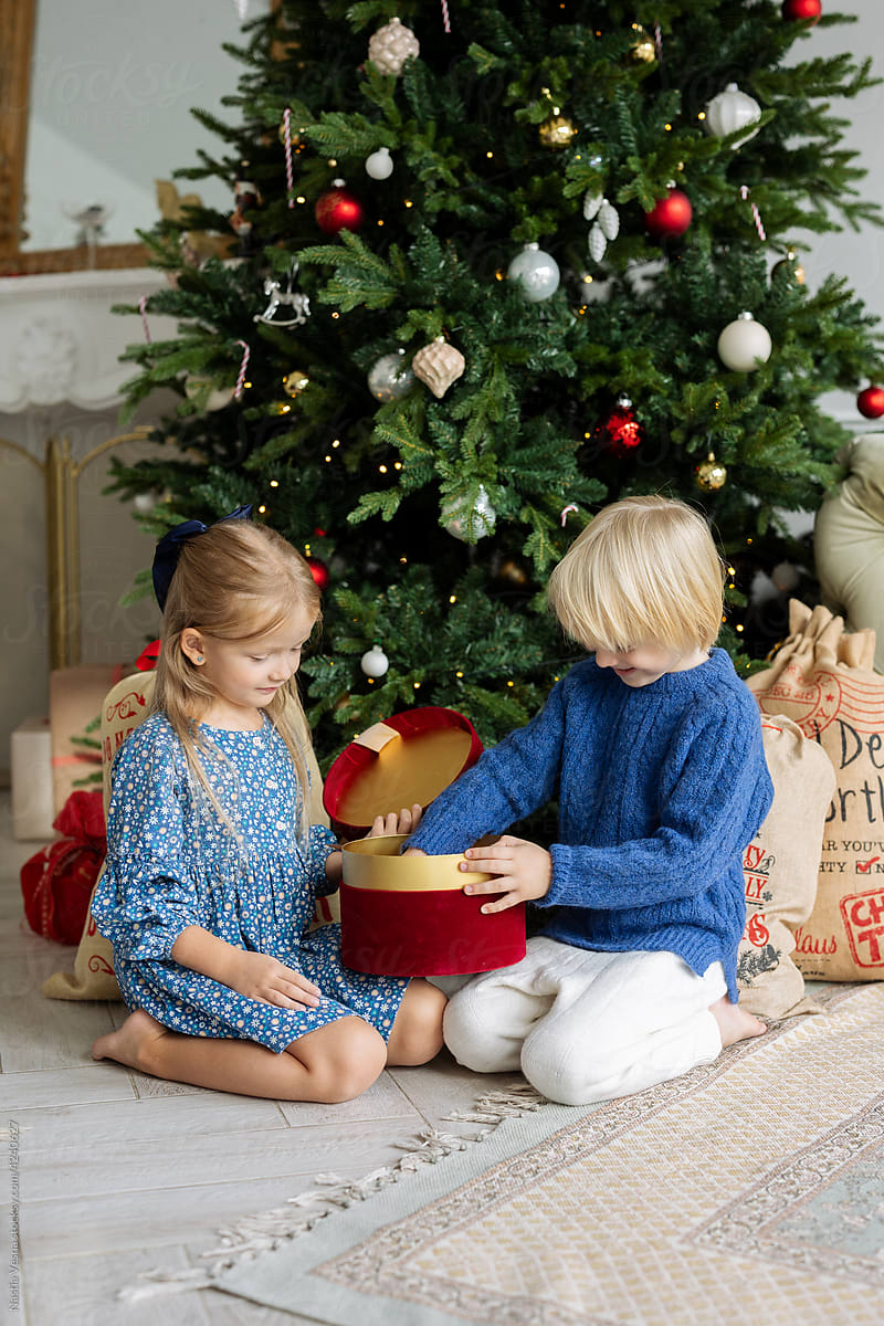 Kids open a gift box near the Christmas tree