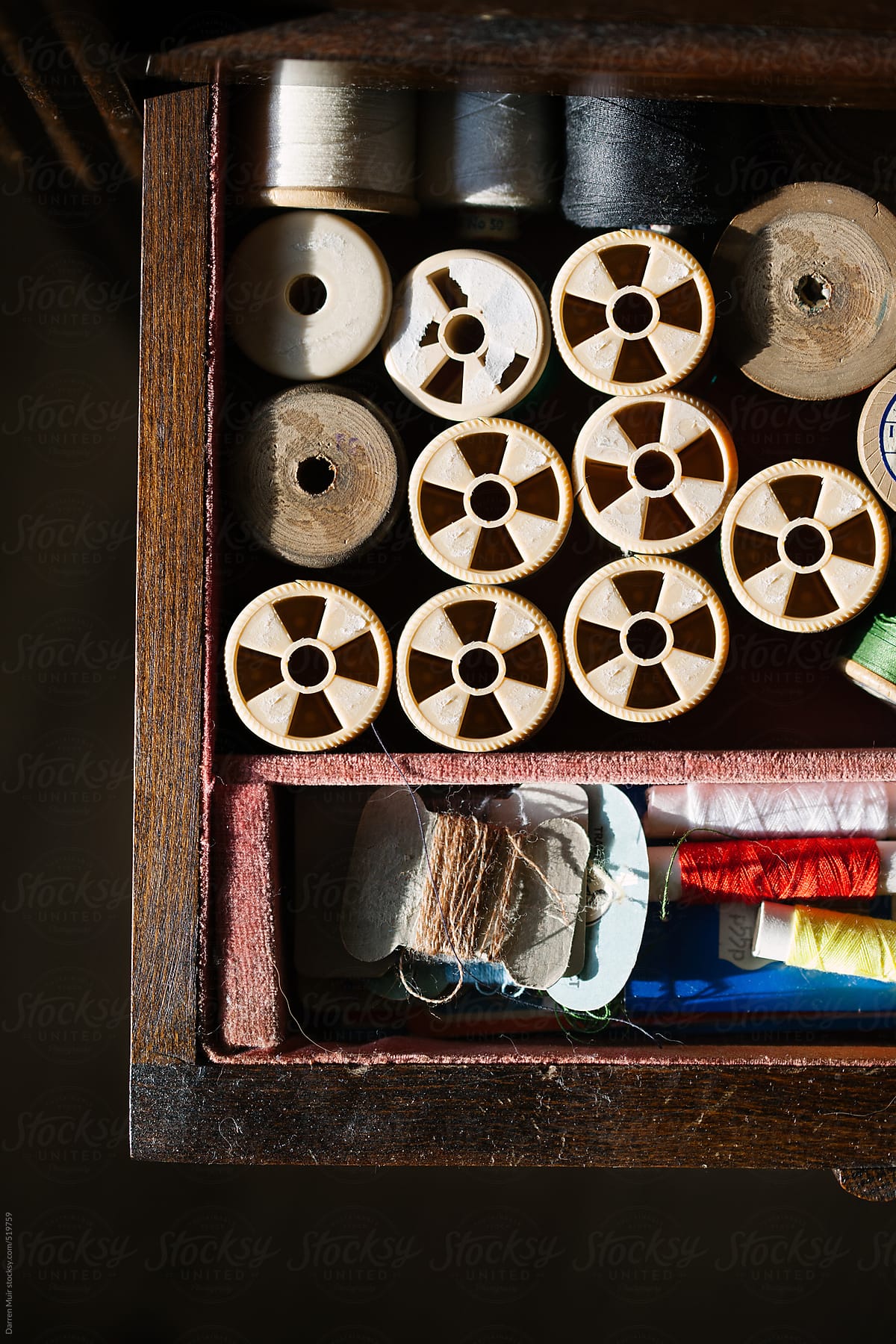 Spools of thread in a sewing box drawer.