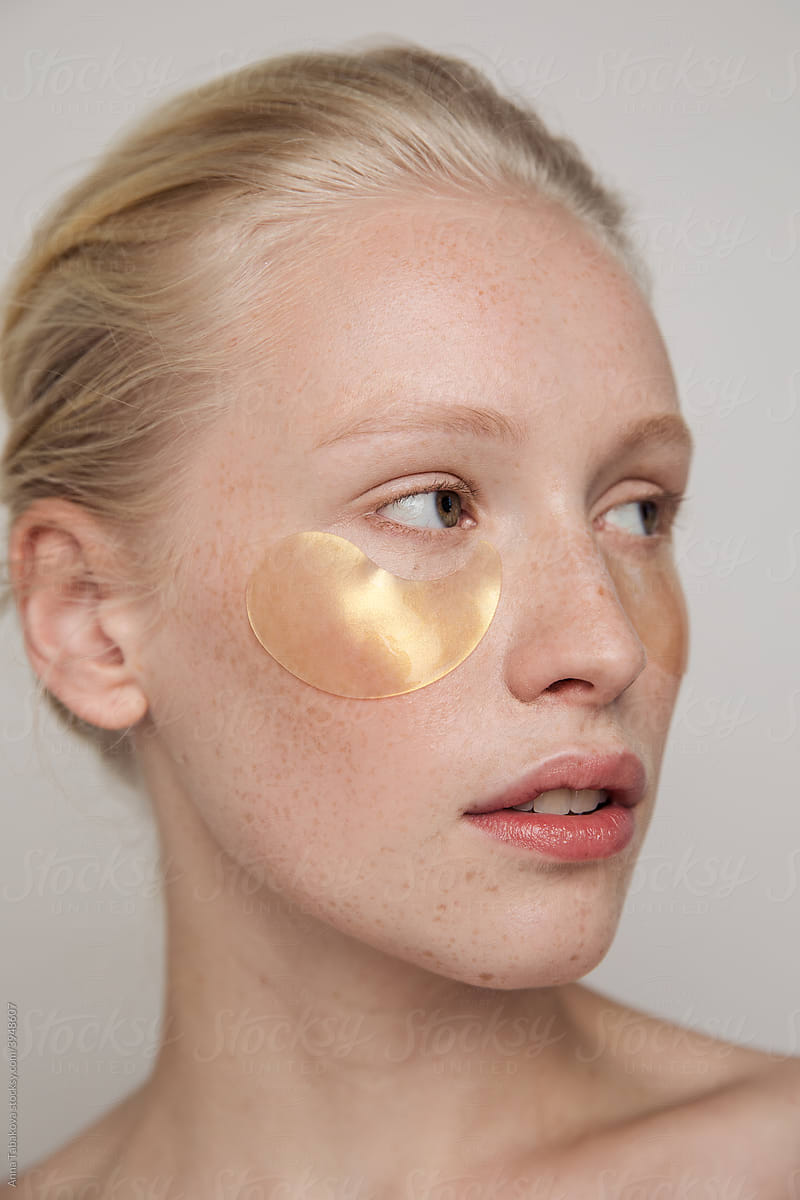 Young freckled model with golden under-eye patches