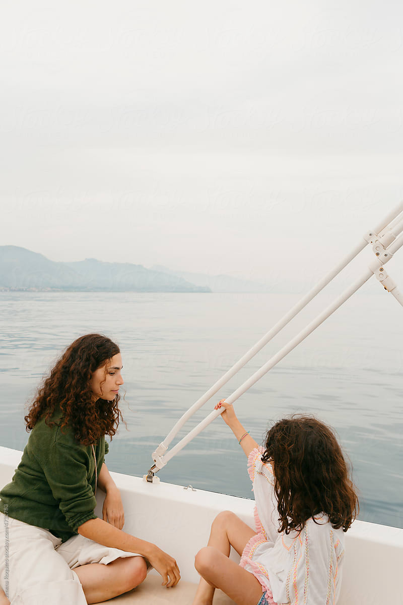 Woman and kid aboard a small boat sailing on coastline