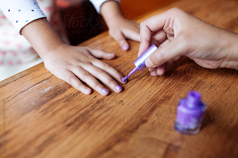 Mother applying nail polish on her daughters nail