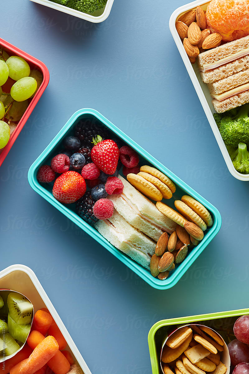 Plastic container with berries, sandwich, cookies.