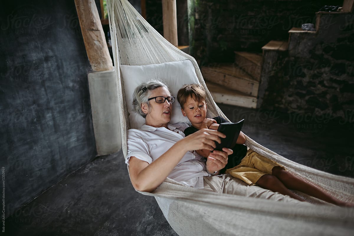 Happy grandma reading with grandson in hammock