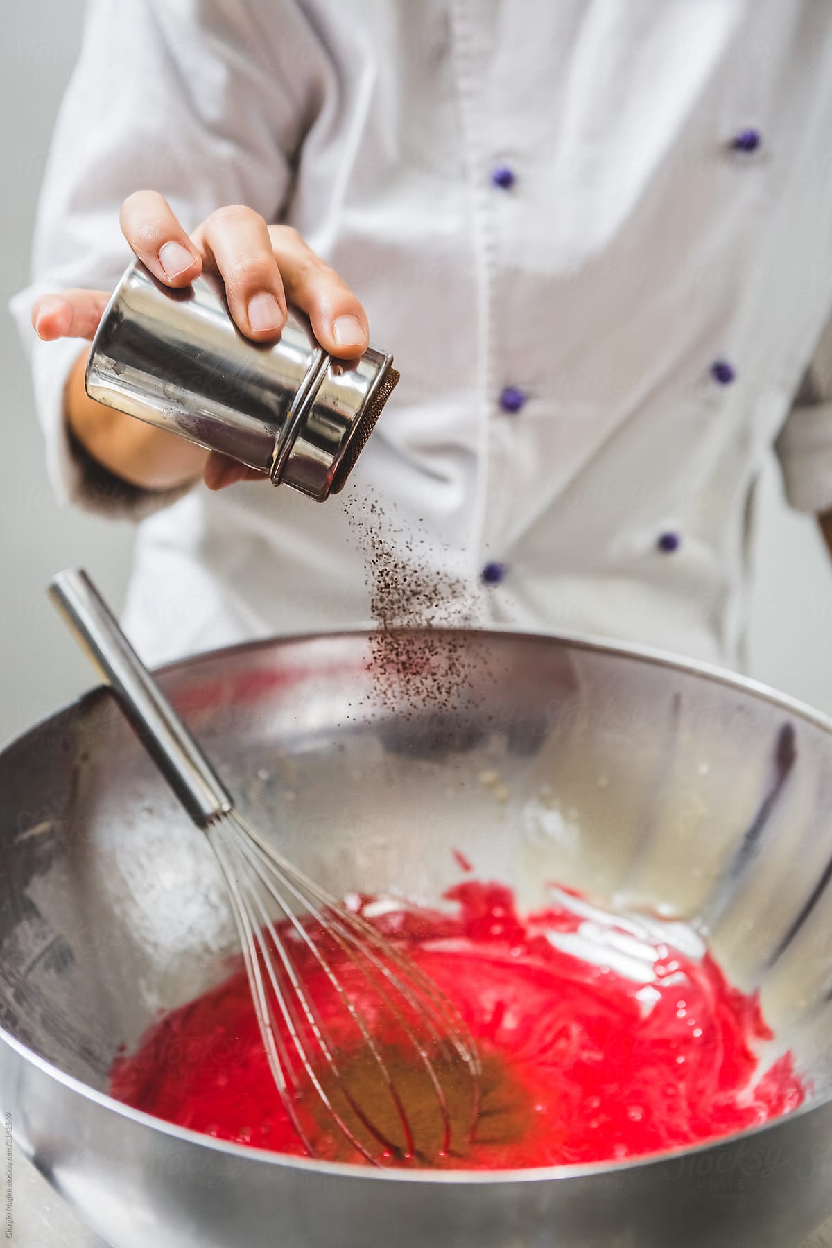 Pastry Chef Adding Cocoa Powder in a Bowl of Red Batter
