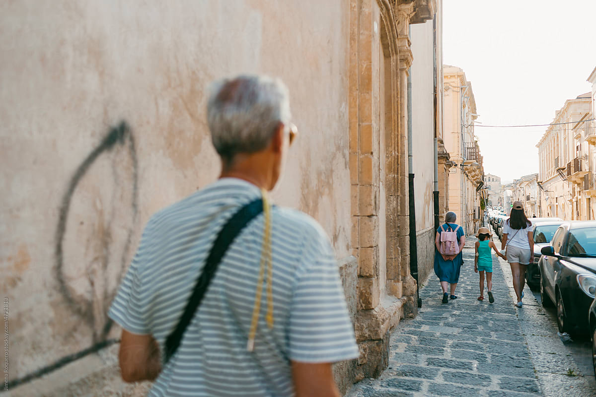 People walking on the sidewalk of an old Italian City.