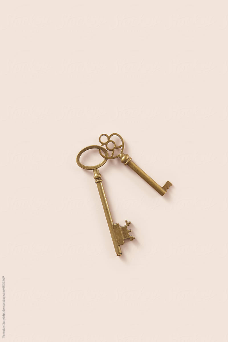 Two antique keys lying connected on beige background