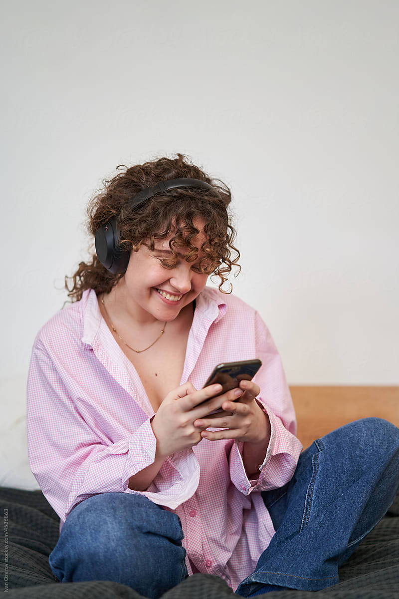 Cheerful woman enjoying music and using smartphone