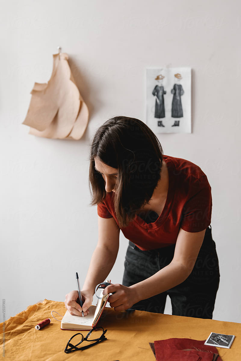 Woman tailor writing in daily notes.