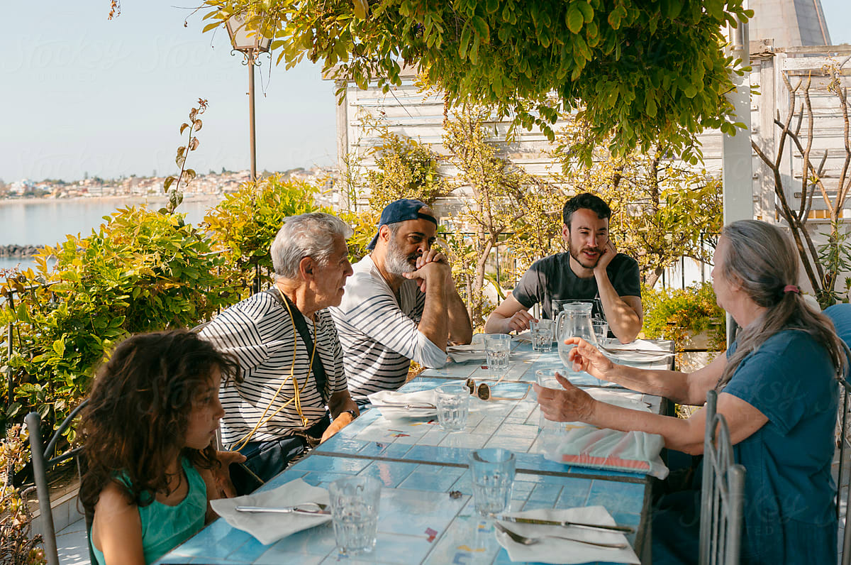 Multigenerational group of people sitting by restaurant terrace table