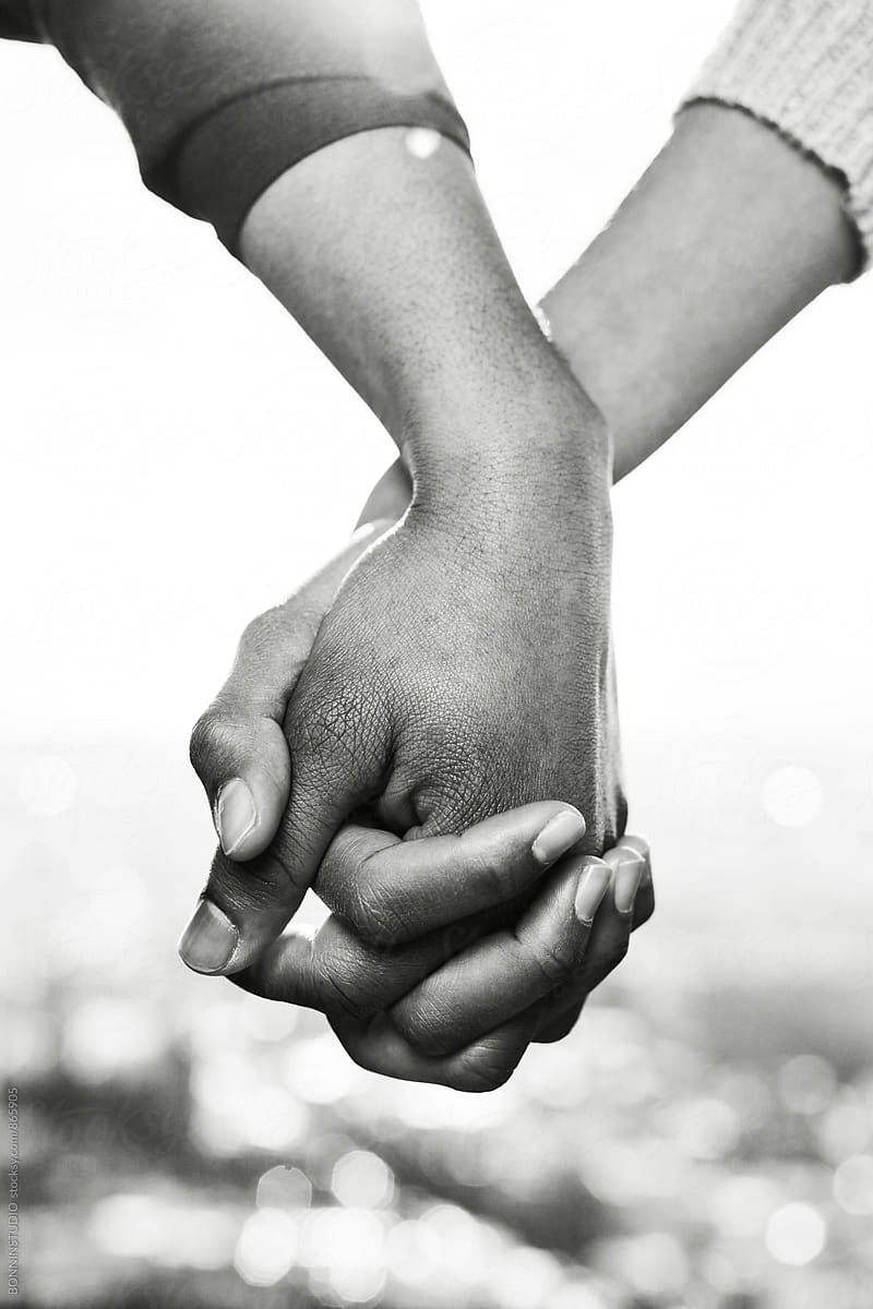 Closeup of couple holding hands outside. Black and white photo.
