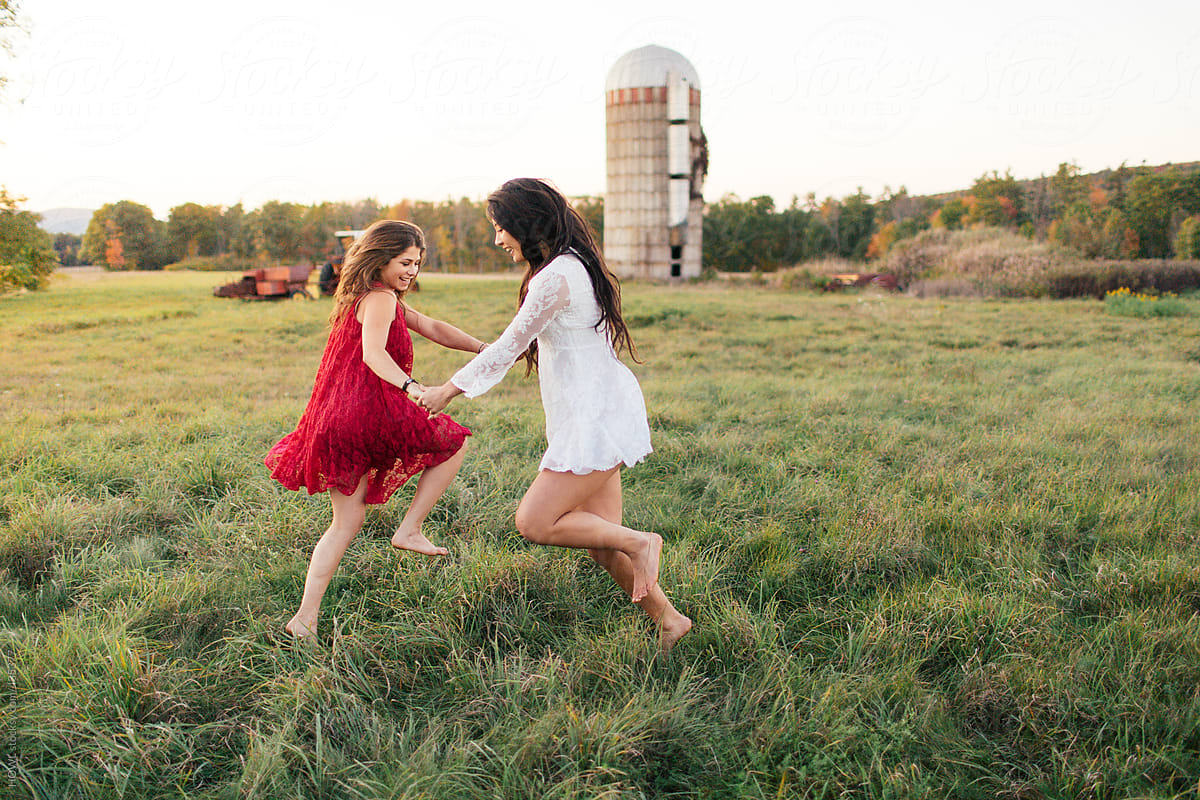 Two friends  hold hands and dance in field