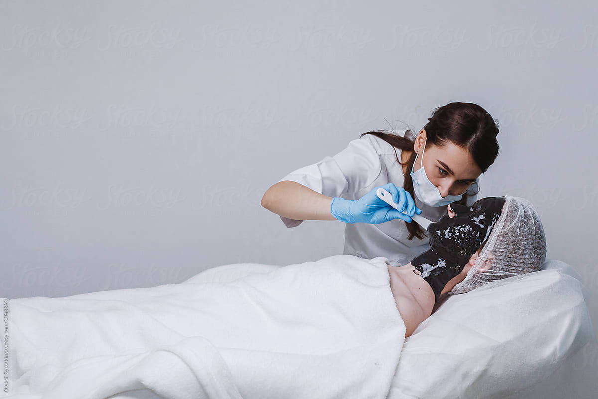 Doctor applying black mask on girl face.