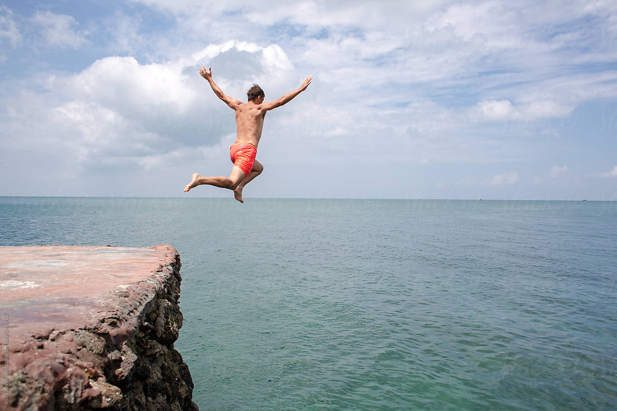 Man Jumping Off Cliff Into The Ocean By Stocksy Contributor Jovo Jovanovic Stocksy