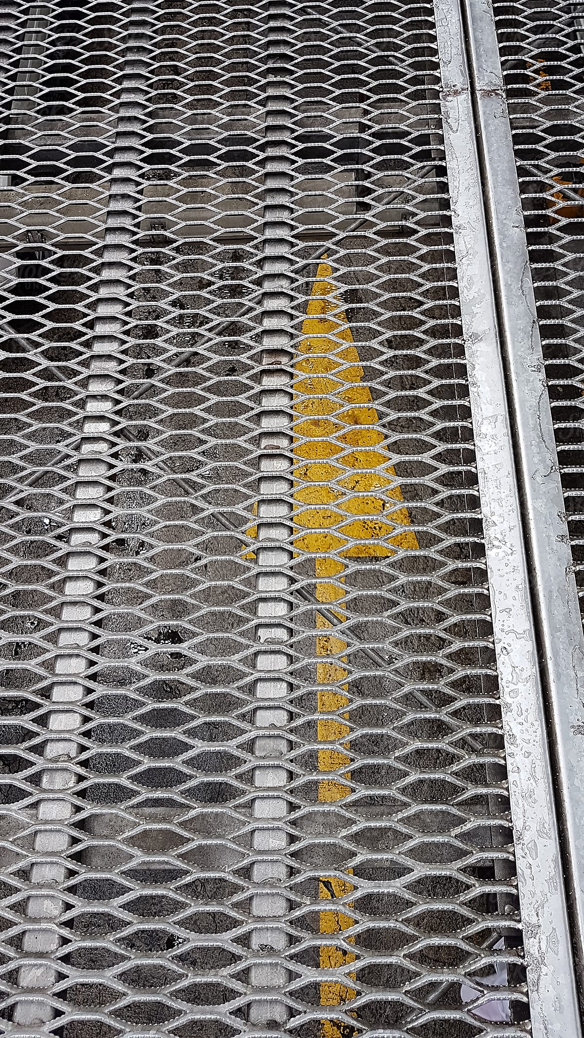 View of ground level parking from the steel mesh flooring of a temporary parking building.