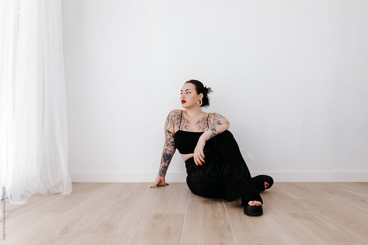 Serious tattooed woman sitting in studio