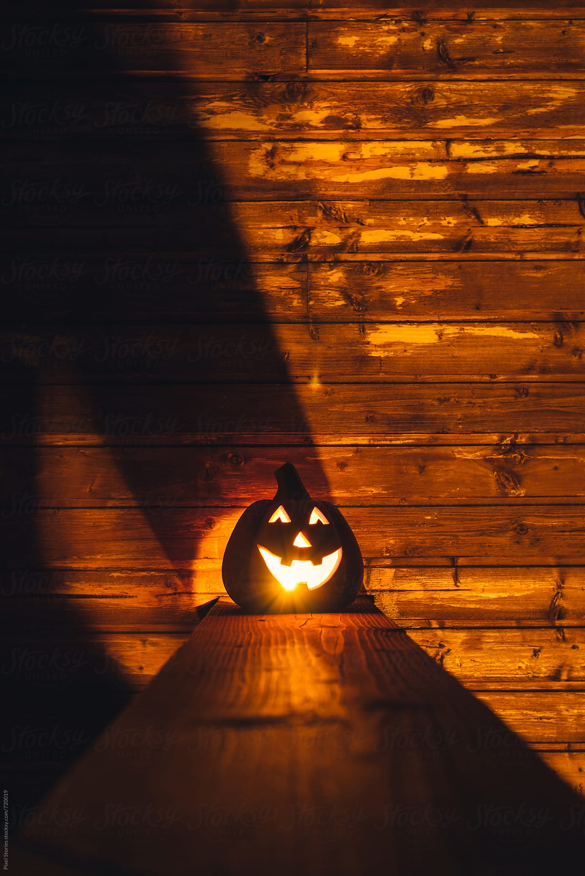 Ceramic pumpkin with lit candle on porch