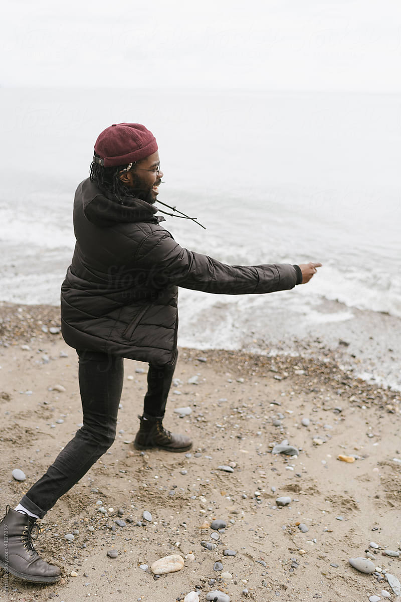 Young Black man Throwing Pebbles on the Beach