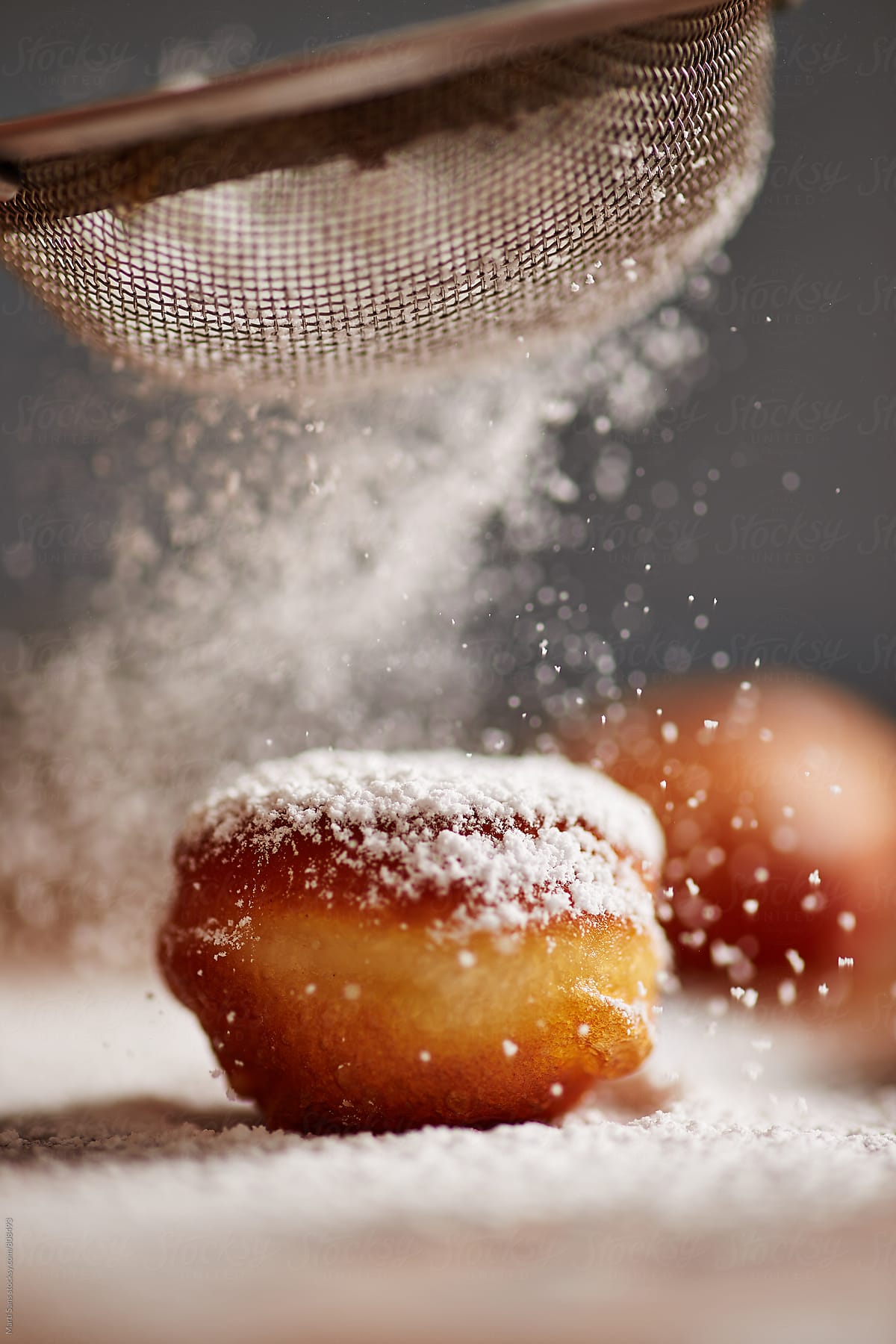 Dusting icing sugar on donut holes