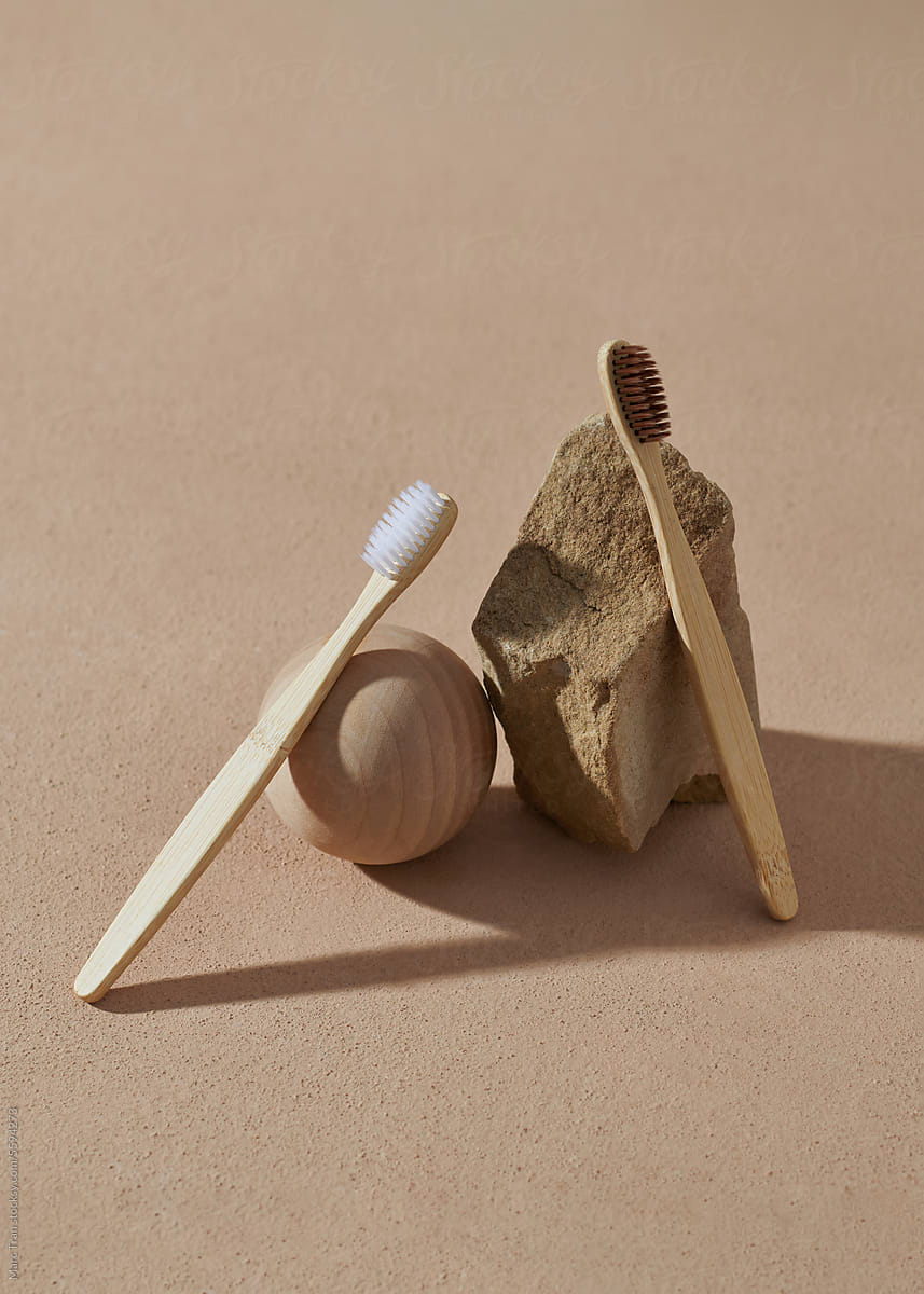 Bamboo toothbrushes with stones on a beige background.
